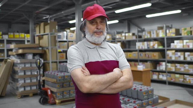 Portrait of mature warehouse worker in uniform standing in distribution center