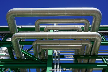 Insulated pipes installed on the steel structure in the power plant and have a sky background.