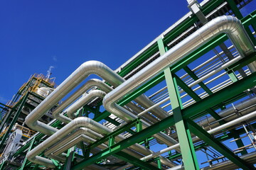 Insulated pipes installed on the steel structure in the power plant and have a sky background.