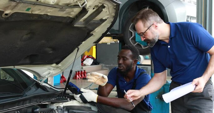 Professional car mechanic repair service and checking car engine by Diagnostics Software computer. Expertise mechanic working in automobile repair garage.
