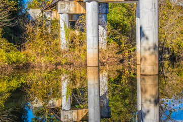 Fototapeta premium Bridge columns reflection in a calm river in the Fall