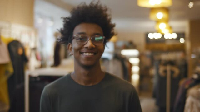 Portrait of hipster young african man smiling at camera standing in clothes store