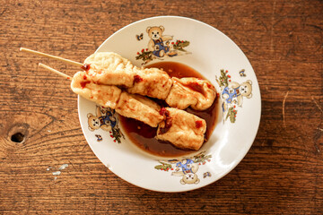 Top view snack vegan food (fried tofu with sauce) in white ceramic plate on wooden background. Thai and Chinese people popular eaten vegan foods in Chinese vegetarian festival in October every years.