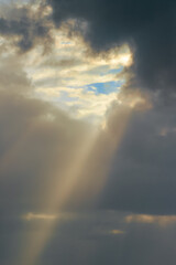 Fototapeta na wymiar Sunbeams shine through the storm clouds after tropical storm