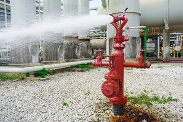 Fototapeta na wymiar Water flowing vigorously from open fire hydrant as part of the fire extinguishing system testing for safety in the event of an emergency in chemical plants, power plants, oil & gas industry.