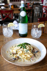 Italian food in a fancy restaurant with a bottle of water