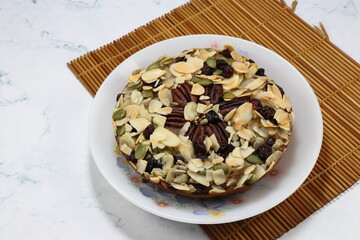 Classic baked banana cake topping with mixed nut and grain on the plate. Famous traditional sweet dessert in Asia bakery shop. 
