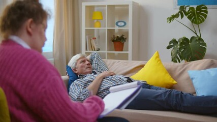 Woman psychologist taking notes listening to senior man patient at psychotherapy session