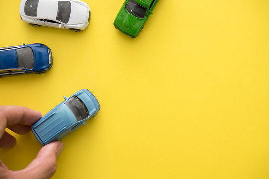 Cropped Hand Holding Toy Car Against Yellow Background