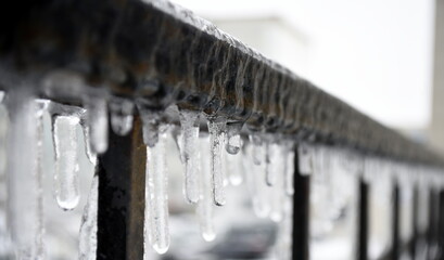 Naklejka na ściany i meble Selective focus of icicles on the railing on a gloomy winter day
