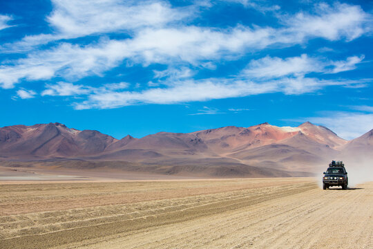 Off-road vehicle driving in the Atacama desert, Bolivia with majestic colored mountains and blue sky in Eduardo Avaroa Andean Fauna National Reserve, Bolivia 2014