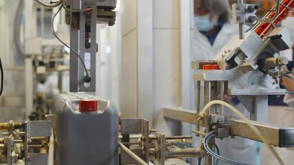 Plastic containers moving on conveyor belt of auto capping and labeling machine at chemical factory