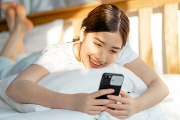 Beautiful Asian woman using her phone when she just wakes up