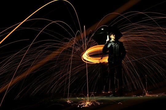 Full Length Of Young Man Spinning Wire Wools While Standing Against Sky At Night