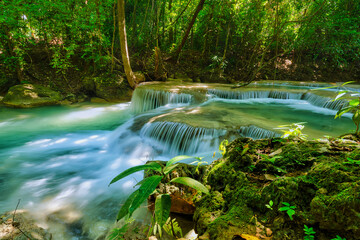 Erawan Waterfall, Kanchanaburi Province Thailand, natural waterfalls, beautiful green forests, with fish in the water as a foreground.