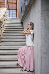 beautiful blond woman posing in pink silk skirt and white silk shirt and pink velvet fabric handemademask