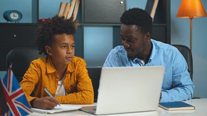 African american father helping son doing homework using laptop - Powered by Adobe