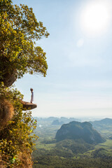 Woman is standing on the edge on the rock, Krabi, Thailand. - 394059469