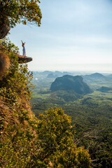 Woman is standing on the edge on the rock, Krabi, Thailand.