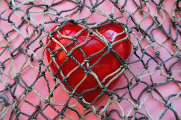 red heart covered with mesh. concept of rejection of love, prohibition of free expression of...