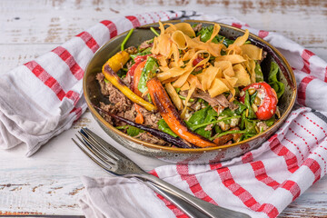 A serving of Lamb Salad in a round bowl with red and white striped napkin