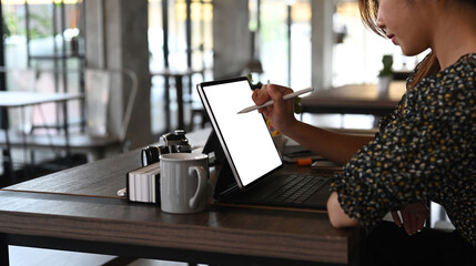 A young businesswoman or graphic designer using stylus pen writing on computer tablet in office.