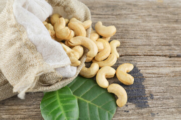 Fototapeta premium Cashew nut in sack bag on wood table background