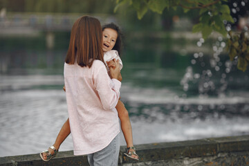 Beautiful family in a park. Woman in a blouse. Mother with daughter by the water.