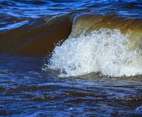 waves run onto the shore and crash against the rocks, creating many splashes and splashes near the shore. river surf in stormy weather near a stone pebble coast with foamy splashing waves.