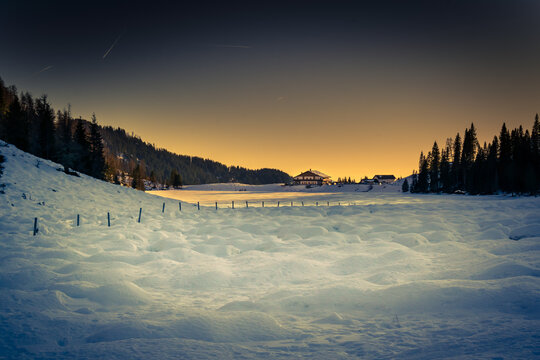 Winter panorama of Calaita Lake at twilight. Frozen lake, fir forests and snowy meadows. Lozen Valley, Trentino-Alto Adige