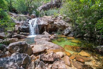 Fototapeta na wymiar Cascading water at Boulder Creek with lush bushland greenery and fallen trees in the tropical Northern Territory at the top end of Australia.