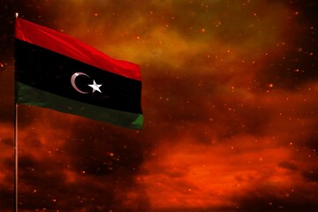 Fluttering Libya flag mockup with blank space for your text on crimson red sky with smoke pillars...