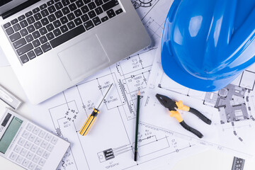 Hand over construction plans with yellow helmet. laptop and drawing tool