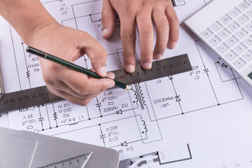 Hand over construction plans with yellow helmet. laptop and drawing tool