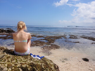 Young woman in deep thoughts looking out over the ocean