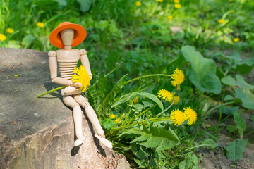 Wooden man and dandelion flower in the park, ecology concept.