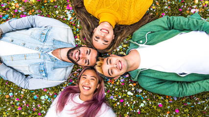 Young friends having fun in the park - Group of happy lying on the grass outdoor looking at camera - Bright filter