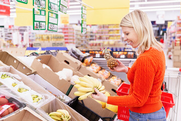 Blonde woman chooses fruits in the supermarket.