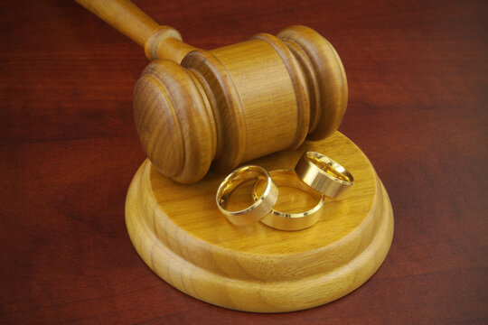Bigamy concept, two wives wedding ring and one husband ring with judge gavel.