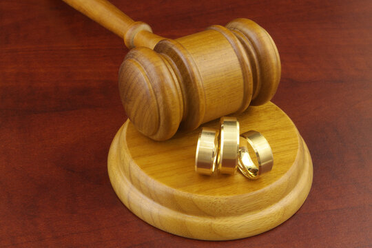 Bigamy concept, two wives wedding ring and one husband ring with judge gavel.