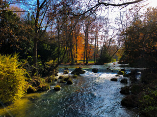 Picturesque Autumn or fall landscape nature scenery at Eisbach river in public park English Garden...