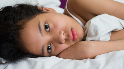 Portraits of beautiful young girl laying down on the bed.