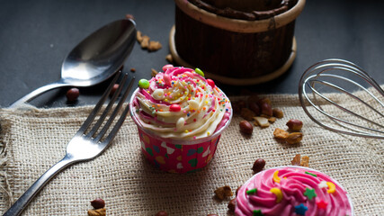 Cupcakes with cute colourful tiny topping in different shapes and Chocolate chips cookies on the black background, text and copy space available.