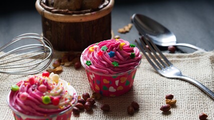 Cupcakes with cute colourful tiny topping in different shapes and Chocolate chips cookies on the black background, text and copy space available.