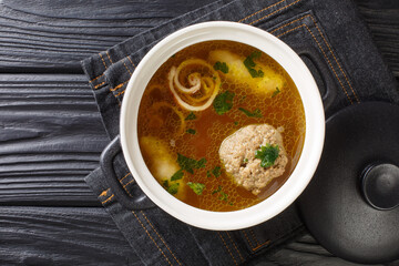 Delicious Viennese rindsuppe soup based on beef broth with dumplings close-up in a saucepan on the...