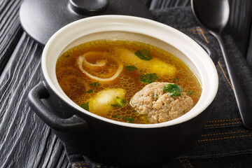 Delicious Viennese rindsuppe soup based on beef broth with dumplings close-up in a saucepan on the table. horizontal