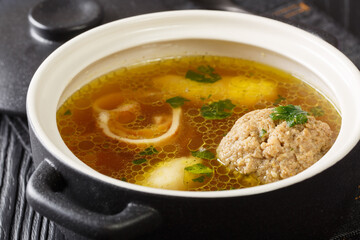 Beef broth or Rindsuppe is the most popular of Austria’s with pancake strips Frittaten, semolina dumplings, liver dumpling close-up in a saucepan on the table. horizontal