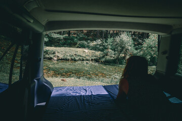 Woman views from the mattress of the van to the river