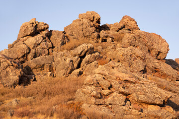 Fototapeta premium Rocks on top of a hill in the Golden hour against the blue sky. Natural abstract background