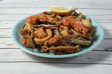 Ration of fried fish (squid, cod, anchovies, baby chopitos and bienmesabe) on wooden table